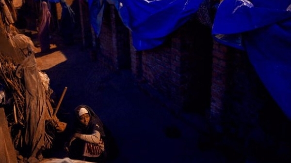 An Indian woman prepares food for dinner at the site of a makeshift home in front of the Jawaharlal Nehru Stadium in New Delhi, India. (Daniel Berehulak/Getty Images)