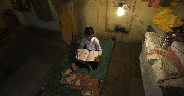 A boy studies under an electric lightbulb in Haryana (Priyanka Parashar/Mint via Getty Images)