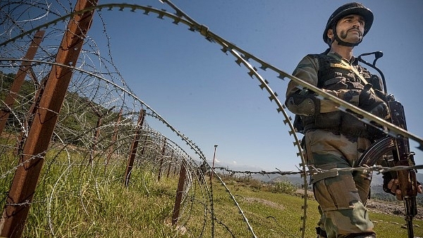 An Indian Army soldier patrols on the fence near the India-Pakistan LOC in Chakan-da-Bagh area near Poonch. (Gurinder Osan/Hindustan Times via Getty Images)