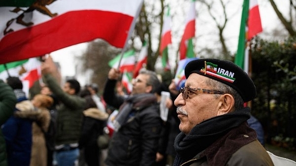 A man wearing an Iran beret stands with anti-regime protesters as they demonstrate outside the Iranian embassy in London, England. (Leon Neal/Getty Images)