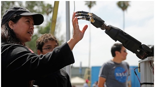 A woman reaches to touch a robotic arm developed by the Johns Hopkins University Applied Physics Laboratory is on display at the Defense Advanced Research Projects Agency (DARPA) Robotics Challenge Expo at the Fairplex June 6, 2015 in Pomona, California. (Chip Somodevilla/Getty Images)