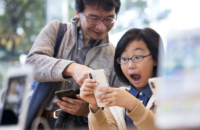 A girl reacts as she tries an iPhone X at the Apple Omotesando store in Tokyo, Japan. (Tomohiro Ohsumi/Getty Images)