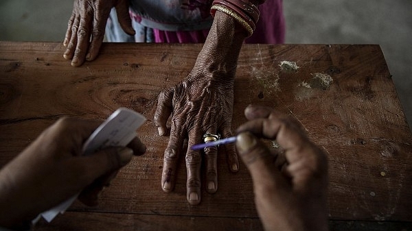 An Indian woman has her finger inked by an election worker before voting. (Kevin Frayer/Getty Images)