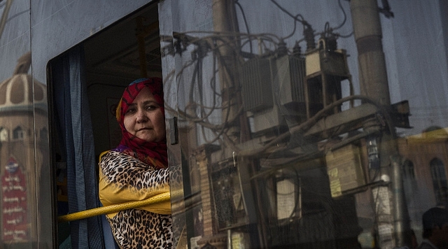 A Uyghur woman looks out the window as she rides in a bus. (Kevin Frayer/Getty Images)