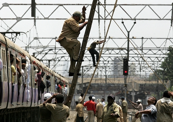 Railway workers repair overhead wire which was snapped between at between Khar and Santacruz. (Satish Bate/Hindustan Times via Getty Images)