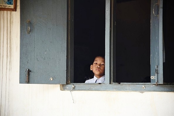 A child looking out of a school window (BIJU BORO/AFP/Getty Images)