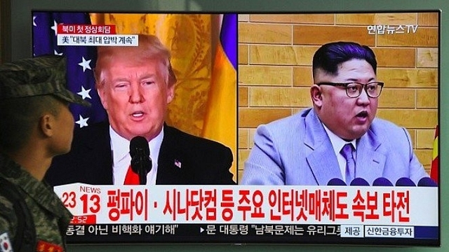 A South Korean soldier walks past a television screen showing pictures of US President Donald Trump (L) and North Korean leader Kim Jong Un at a railway station in Seoul. (JUNG YEON-JE/AFP/Getty Images)