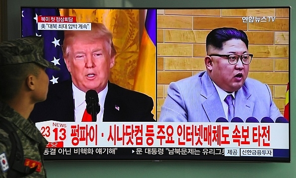 A South Korean soldier walks past a television screen showing pictures of US President Donald Trump (L) and North Korean leader Kim Jong Un at a railway station in Seoul on March 9, 2018. U/ AFP PHOTO / Jung Yeon-je (Photo credits: JUNG YEON-JE/AFP/Getty Images)