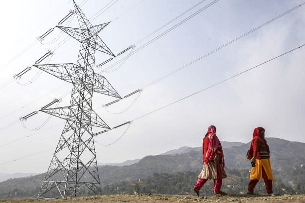 Woman walk past a Sterlite Power Transmission Ltd. transmission tower in Rajouri . (Dhiraj Singh/Bloomberg via Getty Images)