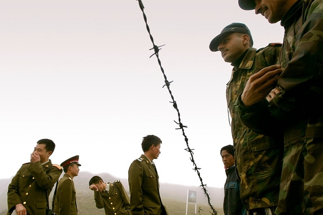 Indian soldiers and Chinese soldiers stand on either side of barbed wire on the border fence at Nathu La. (Sumeet Inder Singh/The India Today Group/Getty Images)&nbsp;