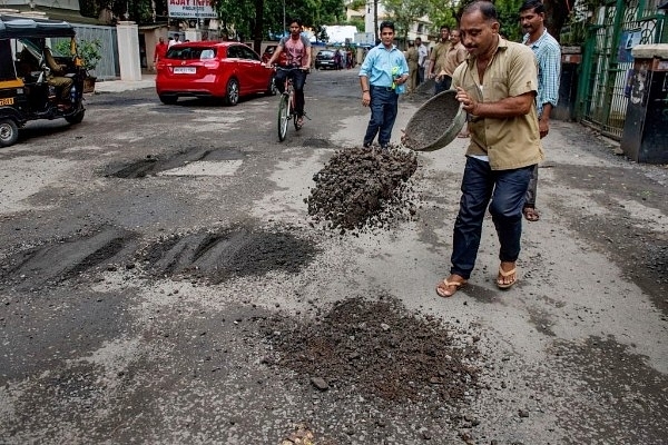 Municipal Corporation workers repairing potholes in Mumbai (Satish Bate/Hindustan Times via Getty Images)