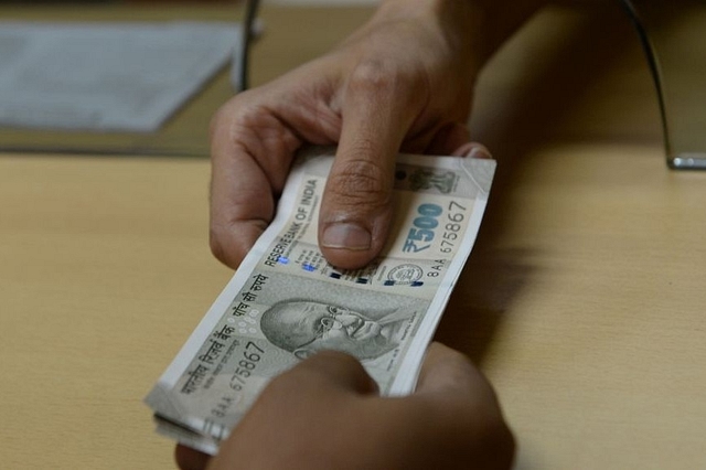 A bank staff member hands Indian 500 rupee notes to a customer on November 24, 2016, in the wake of the demonetisation of old 500 and 1000 rupee notes in Mumbai. (INDRANIL MUKHERJEE/AFP/Getty Images)