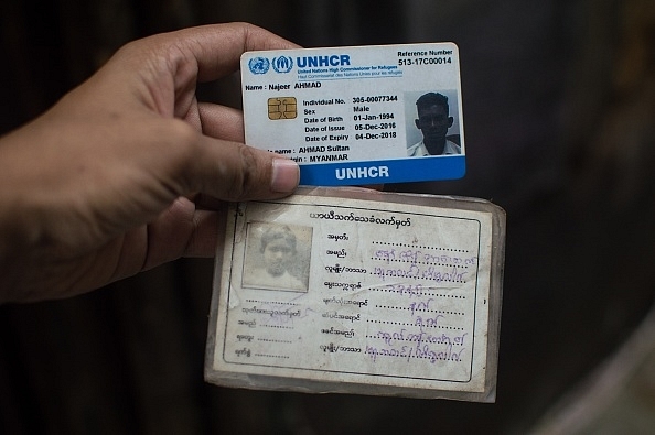 A Rohingya man in New Delhi holds up his refugee card issued by UNHCR. 