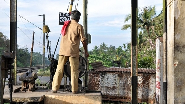 A railway gatekeeper closes the gate at a level crossing. (Image- Joe Ravi via Wikimedia Commons)