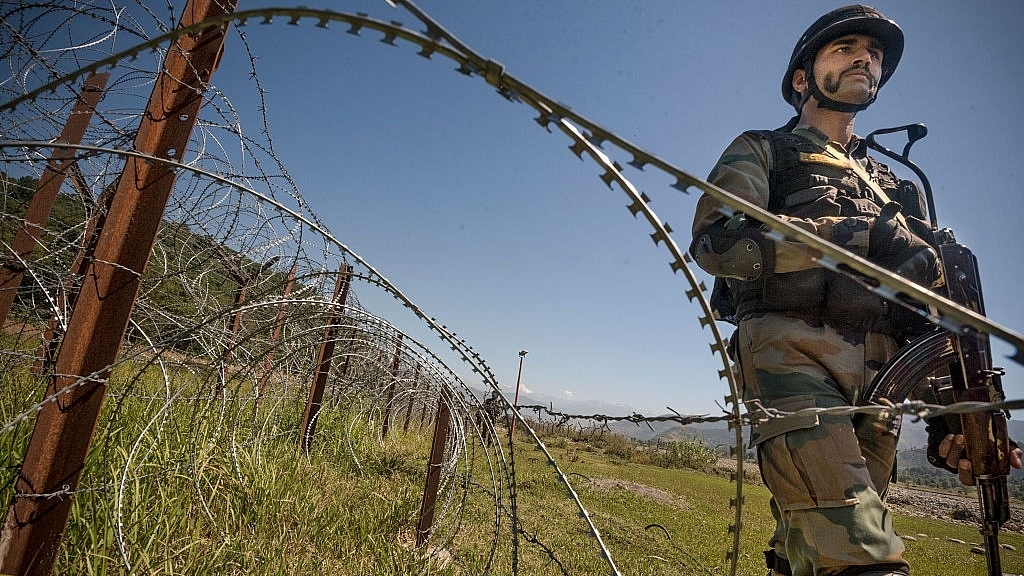 An Indian Army soldier patrols on the fence near the India-Pakistan LOC. (Gurinder Osan/Hindustan Times via Getty Images)