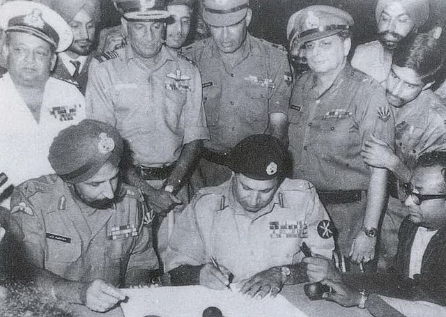 Lt Gen Niazi signing the instrument of surrender (1971) under the gaze of Lt Gen Aurora as other army officials look on.