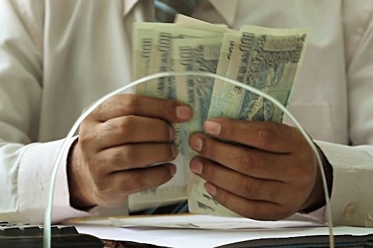 A bank teller counts notes. (GettyImages)