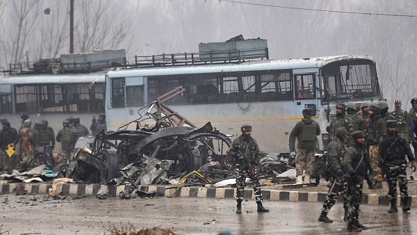 Security forces near the damaged vehicles at Lethpora on the Jammu-Srinagar highway. (Waseem Andrabi/Hindustan Times via Getty Images)