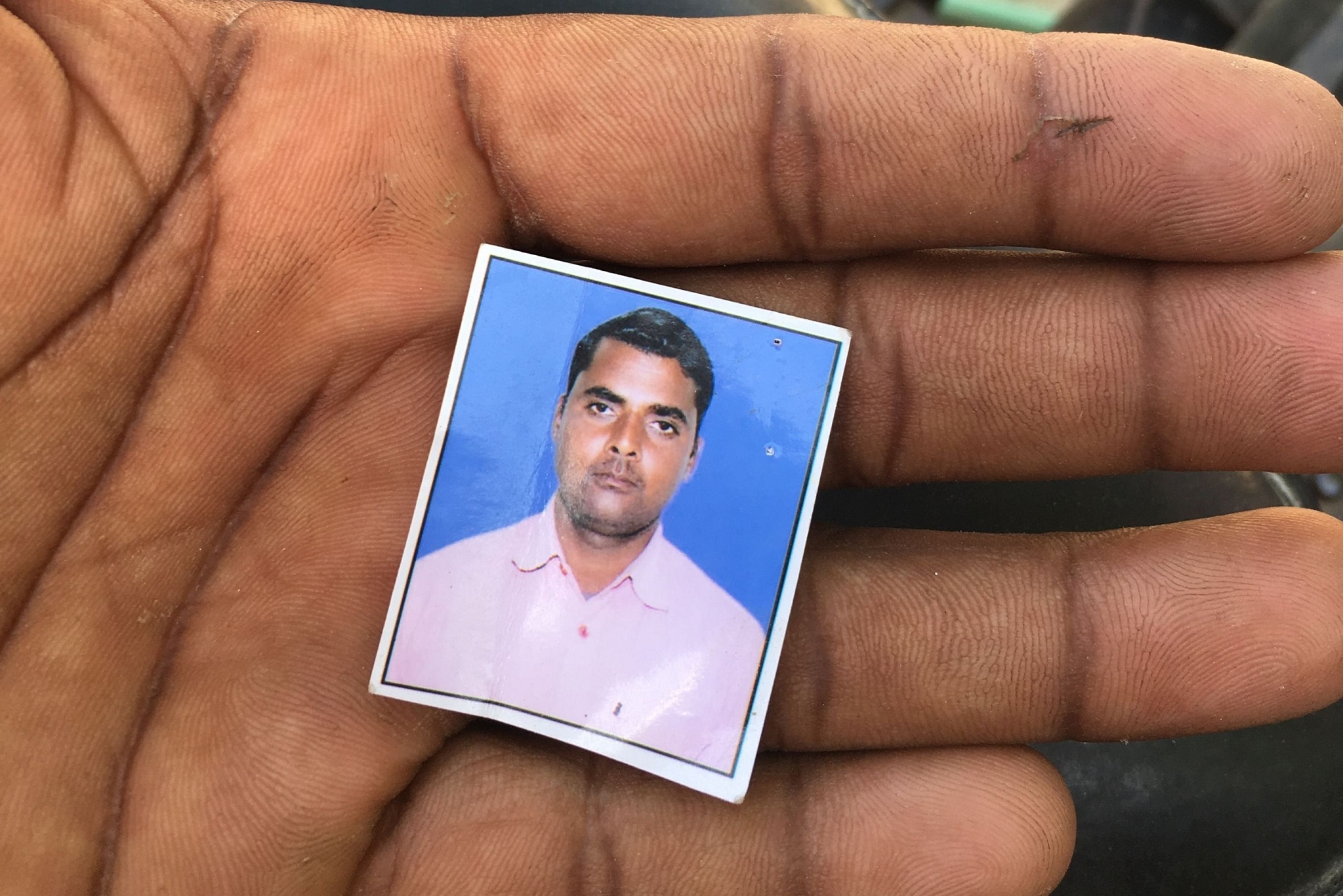 A relative holds the photo of Vinay Saroj