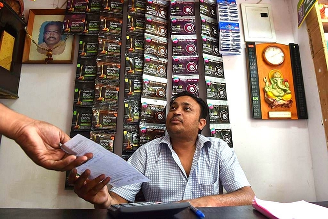 An Indian shopkeeper hands a bill to a customer at his shop in New Delhi. (SAJJAD HUSSAIN/AFP/GettyImages)