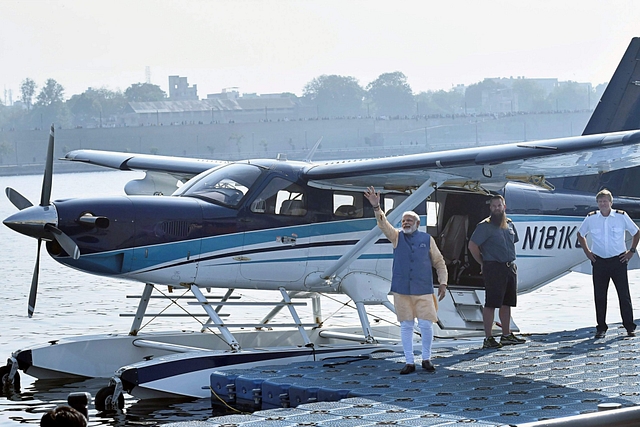 Prime Minister Narendra Modi waving to the crowd next the seaplane in Ahmedabad. (PTI)