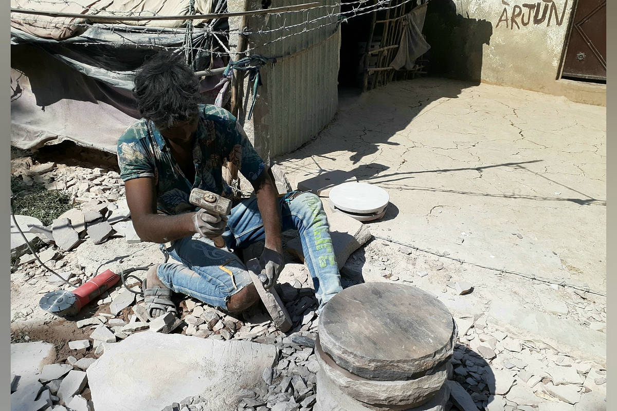A Gond man preparing the grinder.