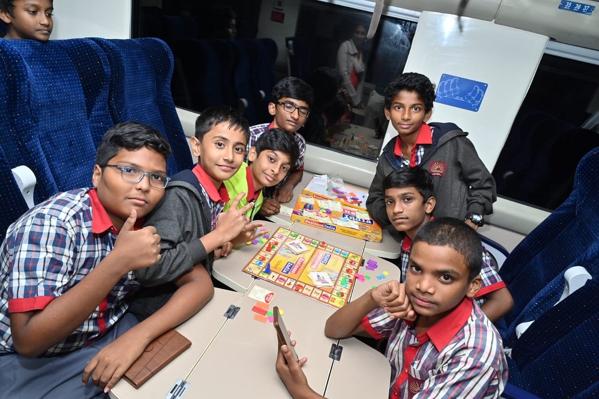 School kids playing the snakes and ladders game onboard.