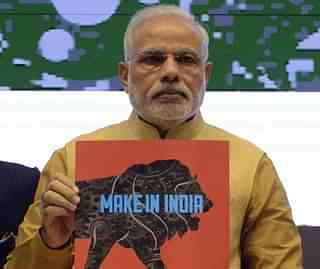 PM Modi displaying a Make In India brochure (AFP PHOTO/RAVEENDRAN)