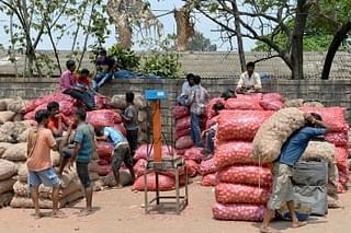 Indian labourers go about their business around sacks of onions at the APMC yard in Bangalore. (Manjunath Kiran/AFP/Getty Images)