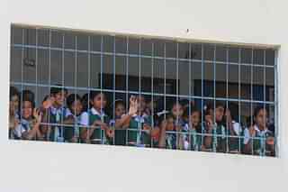 Students look outside the window in an Indian school.  