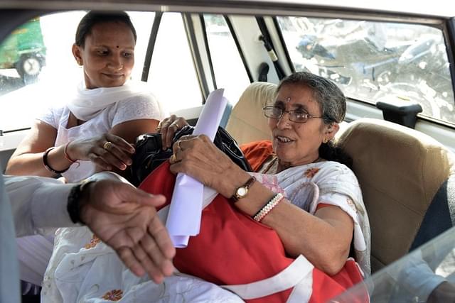 Jashodaben (R) holds a copy of the Right To Information (RTI) application filed by her.