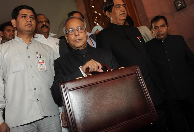 Indian finance minister Pranab Mukherjee (C) poses for the media in parliament prior to presenting the national budget in New Delhi on March 16, 2012.  India's government was due to deliver its budget as an acrimonious split in its ranks over hiking rail fares highlighted the increasingly dysfunctional nature of the ruling coalition. The Congress-led administration, already battered by a string of graft scandals, is under financial market pressure to cut public spending and rein in a ballooning deficit at the same time as spurring slowing growth. AFP PHOTO/ Raveendran (Photo credit should read RAVEENDRAN/AFP/Getty Images)
