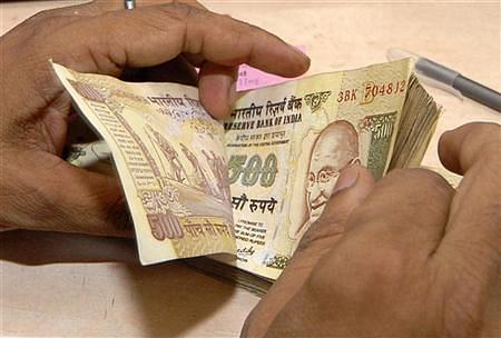 A bank official counts currency notes.
