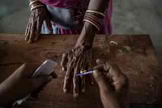 

An Indian woman has her finger inked by an elections worker before voting at a polling station on April 17, 2014. (Kevin Frayer/Getty Images)