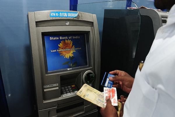 A bank customers withdraws cash from an ATM. (ARUN SANKAR/AFP/GettyImages)