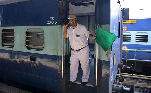 A railway guard signals with a green flag as a train departs from a railway station in Secunderabad. Photo credit: NOAH SEELAM/AFP/GettyImages
