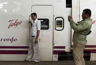  
Bystander poses near train coaches from Spanish manufacturer Talgo. 


(Photo credit: PUNIT PARANJPE/AFP/Getty Images)

