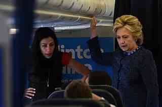 US Democratic presidential nominee Hillary Clinton talks to staff as aide Huma Abedin (L) listens onboard their campaign plane (JEWEL SAMAD/AFP/Getty Images)