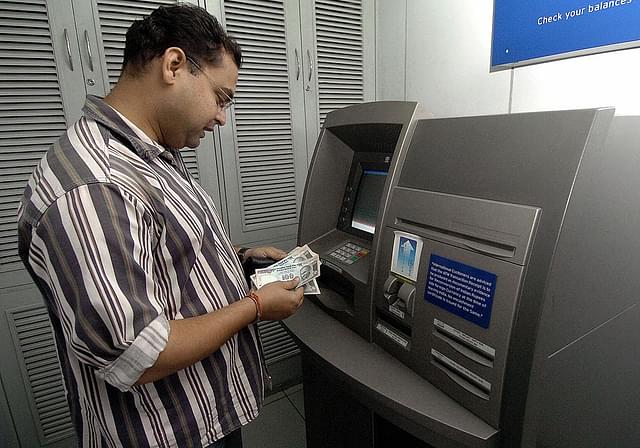 A bank customer withdraws money from an ATM in New Delhi. (Photo credit: PRAKASH SINGH/AFP/GettyImages)