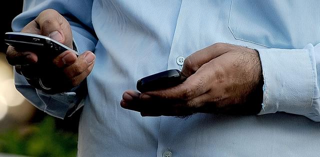 An Indian office-goer checks a text message on his mobile
phone in Mumbai. Photo credit: INDRANIL MUKHERJEE/AFP/GettyImages &nbsp; &nbsp; &nbsp;