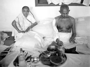 Kasturba watches as Gandhi reads 