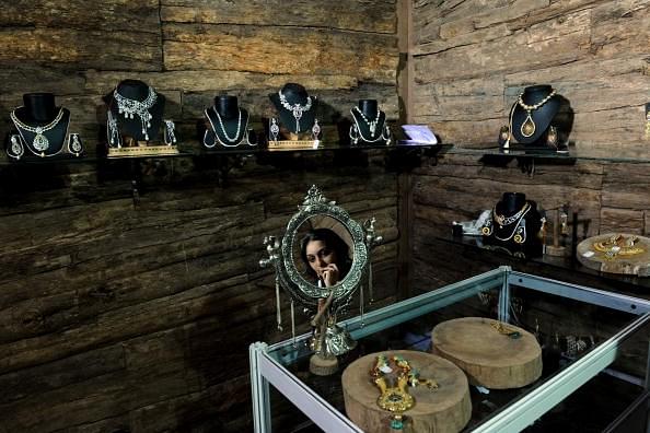 An Indian woman is reflected in a mirror as she tries on jewellery in a stall at a Luxury Trade fair in Mumbai on 7 November 2009. (PAL PILLAI/AFP/Getty Images)
