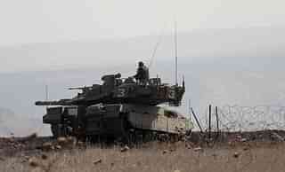 Israeli soldiers on a tank monitor the area near Golan Heights. (Photo credit: JALAA MAREY/AFP/Getty Images)