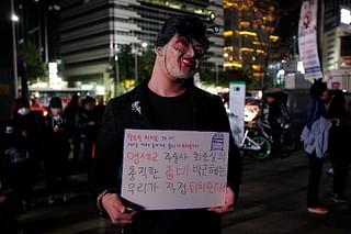 A protester wearing a mask of Park Geun-Hye holds a placard
saying ‘Why do you need Halloween fest? We can see all the horror in our lives’
during a protest on 29 October in Seoul. Photo credit: Woohae Cho/GettyImages &nbsp; &nbsp;  