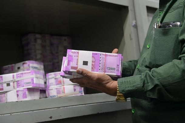 An Indian bank employee checks stacks of new 2,000 rupee notes in Ahmedabad. Photo credit: SAM PANTHAKY/AFP/GettyImages