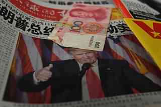 A Chinese newspaper featuring a photo of US President-elect Donald Trump that reads ‘President Trump shakes America’, is partially covered by a 100 Yuan note on a news stand. (GREG BAKER/AFP/Getty Images)