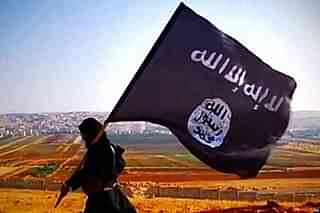 Islamic State fighter carrying their flag (Wikimedia Commons)