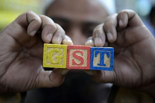 An Indian consumer goods trader shows letters GST representing ‘goods and services tax’. (NOAH SEELAM/AFP/Getty Images)