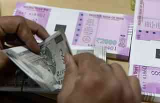 A bank staff member counts Indian 500 rupee notes to give to customers. (INDRANIL MUKHERJEE/AFP/Getty Images) 
