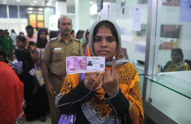 

A Indian woman poses with new 2000 rupee notes, her Aadhaar ID card and a finger inked with indelible ink after exchanging withdrawn 500 and 1000 rupee banknotes at a bank in Chennai on November 17, 2016. (ARUN SANKAR/AFP/Getty Images)